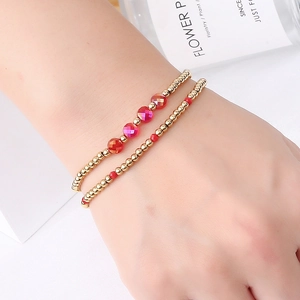 Elastic beaded bracelet with gold stainless steel beads and pink faceted crystal charms