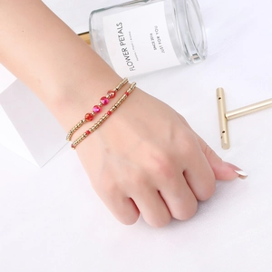 Detail of red faceted crystal beads and gold metal spheres on layered elastic bracelets