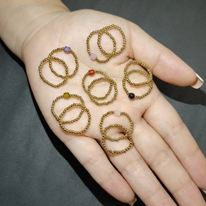 Detailed view of elastic gold bead rings featuring colorful zircon stones on palm