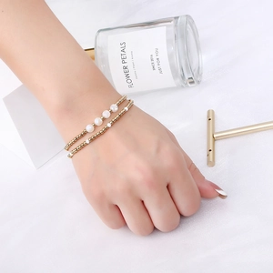 Detail of elegant two-piece gold beaded bracelet set with white faceted crystal stones