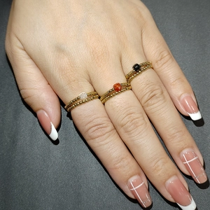 Three-piece set of golden stainless steel beaded rings with zircon stone accents on a hand