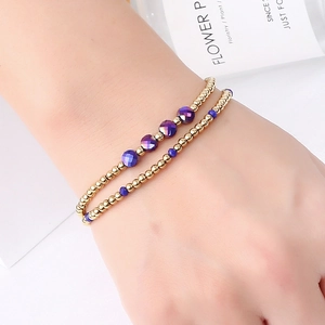 Detailed shot of two layered stretch bracelets with gold beads and faceted purple crystals