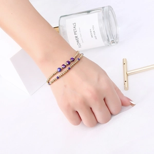 Close-up of double-layered beaded bracelet with gold beads and faceted crystals on model