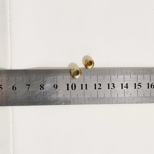 Macro shot of gold-plated spacer beads showing 8mm outer diameter on a scale ruler