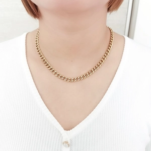 Gros plan détaillé d'un collier à chaîne gourmette dorée porté par un mannequin femme