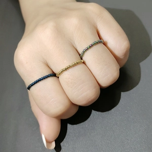 Close-up of three elastic stainless steel bead rings in gold, blue, and rainbow colors
