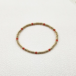 Detail of beaded bracelet with gold stainless steel beads and red faceted crystals