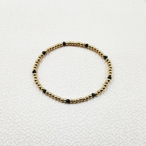 Detailed view of elastic handmade bracelet with gold steel beads and black faceted crystals