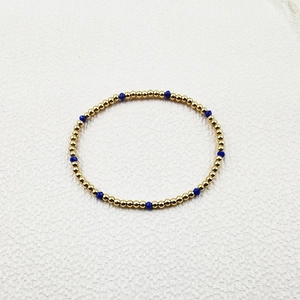 Detailed close-up of handmade gold steel beads and faceted blue crystal stretch bracelet