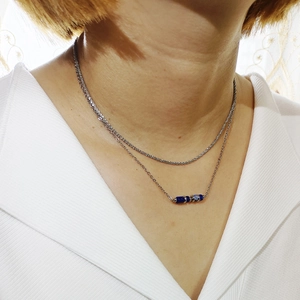 Dettaglio della collana argentata a due strati con perle di pietra blu su catena