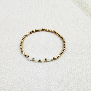 Detailed close-up of gold beaded elastic bracelet with multifaceted white crystal accents