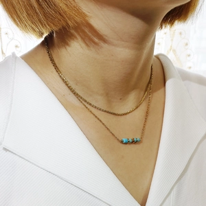 Dettaglio della collana a due strati in acciaio dorato con tre perle di pietra blu