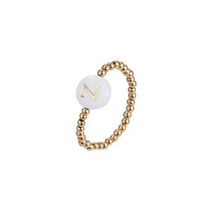 Close-up of gold beaded elastic ring featuring a white shell charm with letter Z engraving