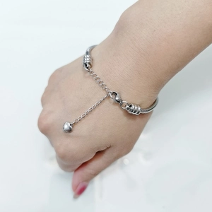Dettaglio bracciale a maglia serpente in acciaio con ciondolo a cuore e chiusura a moschettone