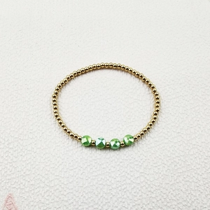 Detail of gold beads and green faceted crystals on a stylish stretch beaded bracelet