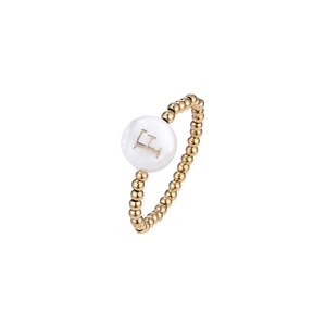 Detail of gold beaded elastic ring featuring a white shell charm with gold letter F