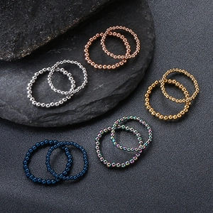 Anillos elásticos de cuentas de acero inoxidable en plata y oro sobre base de piedra negra