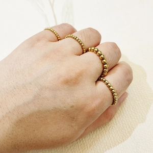 Close-up of golden beaded stainless steel elastic rings stacked on fingers