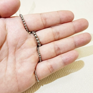 Detail of minimalist silver stainless steel beaded ring held to show flexibility