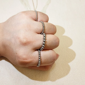 Close-up of silver stainless steel bead rings layered on a hand with metallic shine