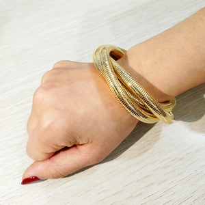 Brazalete de espiral dorado multicapa con diseño apilado y textura de muelle metálico