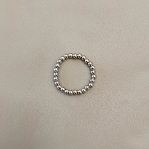 Macro shot of polished silver stainless steel beaded ring on light gray texture