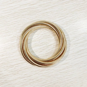 Detalle de brazalete dorado de múltiples capas con diseño de resorte en madera