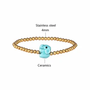 Detail of stainless steel bead bracelet with a light blue ceramic elephant charm and PVD gold