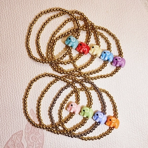 Stack of gold beaded bracelets featuring colorful ceramic elephant charms in various shades