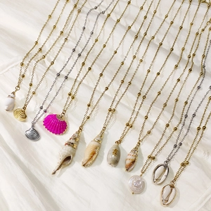 Flat lay of multiple ocean-themed seashell and conch pendants on gold and silver beaded chains
