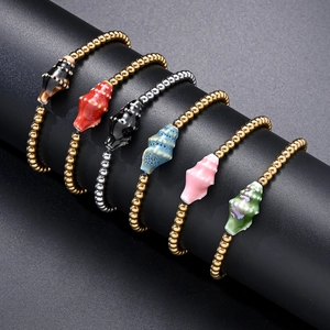 Close-up of ocean-themed beaded bracelets with colorful enamel shell charms on black display