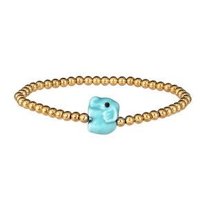 Detail of beaded bracelet with golden beads and a blue ceramic elephant charm