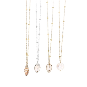 Detail of beach shell pendants and mother of pearl discs on fine gold and silver chains