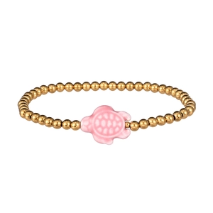 Detail of beaded gold chain bracelet with a pink ceramic sea turtle charm centerpiece