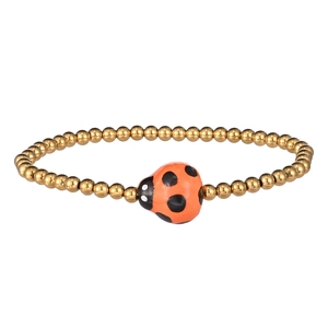 Close-up of golden beaded bracelet featuring a detailed orange and black ladybug charm