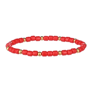 Dettaglio di perline cilindriche rosse e distanziatori dorati su un bracciale boho