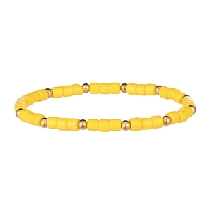 Dettaglio di cilindri in resina gialla e perle metalliche dorate sul bracciale elastico