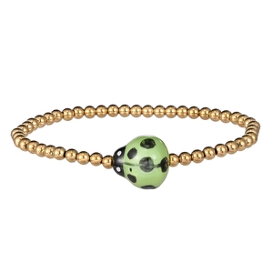 Close-up of golden stainless steel beads and green ceramic ladybug charm on the bracelet