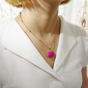 Pink seashell pendant necklace with gold beaded chain shown on a female model