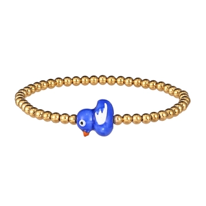 Macro detail of gold beaded bracelet with a cute blue ceramic bird charm and steel beads