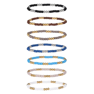 Ensemble de sept bracelets élastiques en perles colorées et acier inoxydable sur fond blanc
