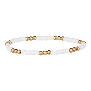 Détail de perles blanches en céramique et dorées en acier sur bracelet élastique