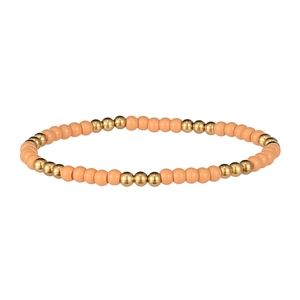 Détail de perles mates roses et dorées sur un bracelet élastique de style bohème chic