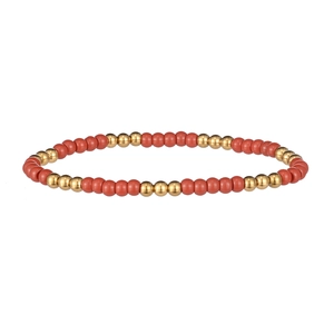 Détail de perles rouges mates et sphères en acier doré sur un bracelet perlé minimaliste