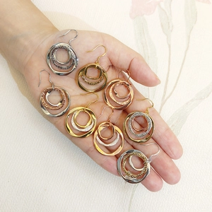 Detail of three-tone interlocking hoop earrings in gold, silver, and rose gold finishes
