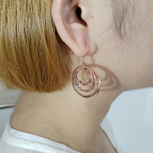 Detail shot of rose gold triple hoop earrings showing three interlocking rings on ear