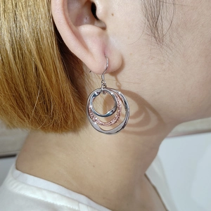 Close-up of mixed metal triple ring drop earrings with silver and rose gold polished finish