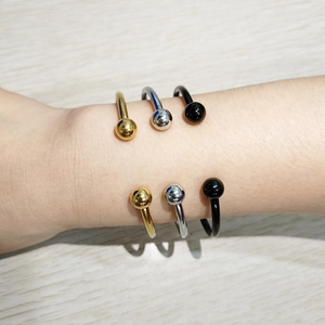 Three minimalist stainless steel C-shaped ball bangles in gold, silver, and black finish