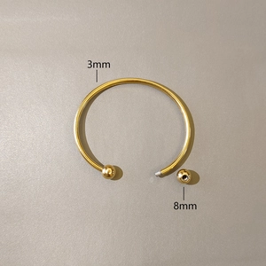 Detail view of 3mm gold stainless steel cuff bracelet with 8mm screw-off ball ends