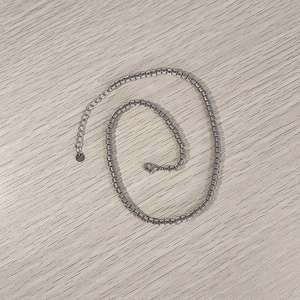 Dettaglio collana con perle argentate a trama diagonale e chiusura a moschettone
